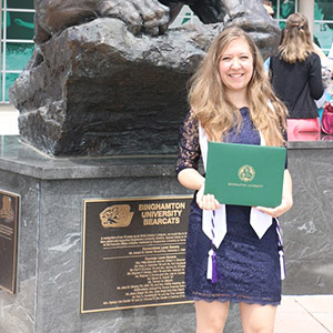 Hannah Watrobski Holding Diploma in front of Binghamton University Statue