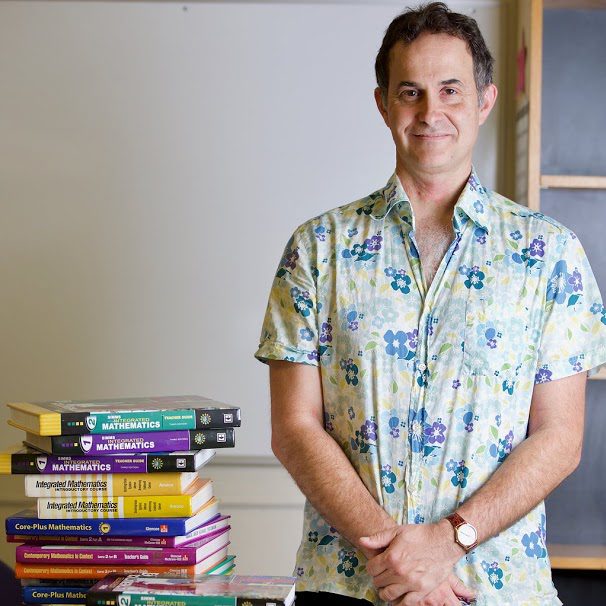 photo of lee kaltman standing next to stack of mathmatics books