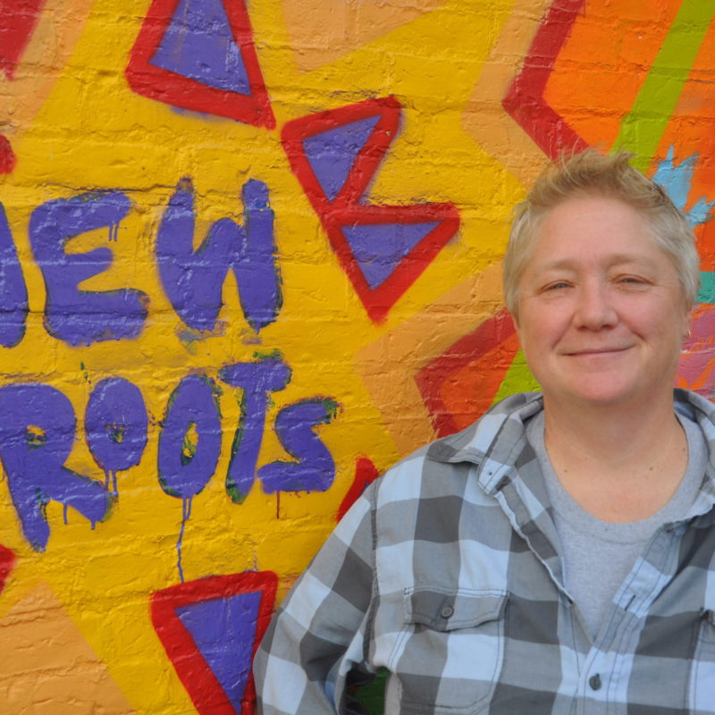 photo of allyn rosenbaum standing in front of mural