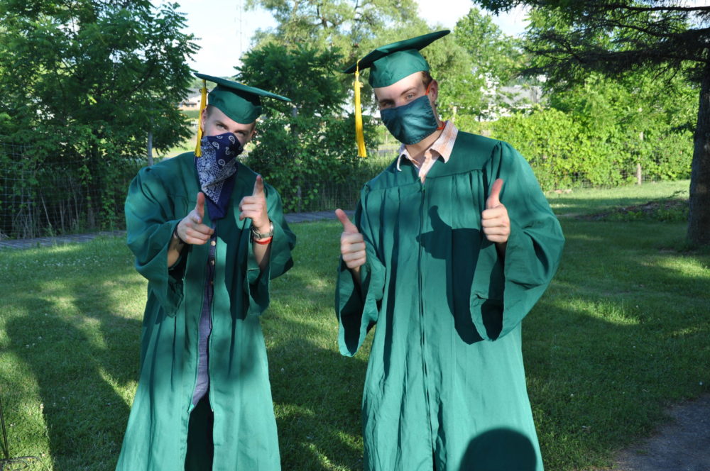 two male new roots school graduates posing outside
