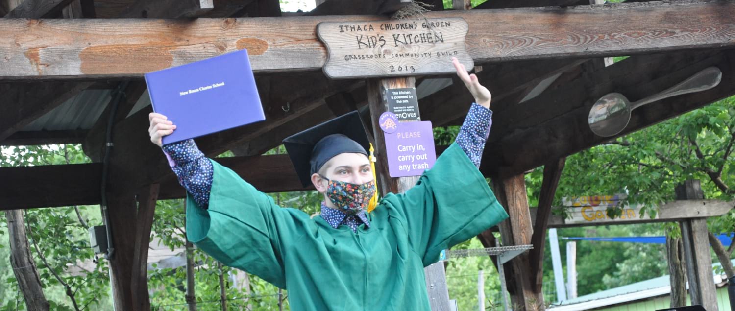 new roots charter school graduate holding up their diploma outside