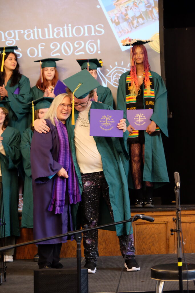 New Roots Charter School Principal Tina gets a hug during the 2026 graduation ceremony